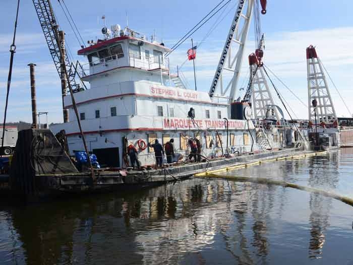 Salvage crews carry sunken towboat image description