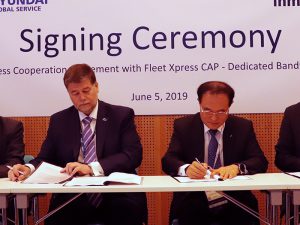 Two men in suits sign documents