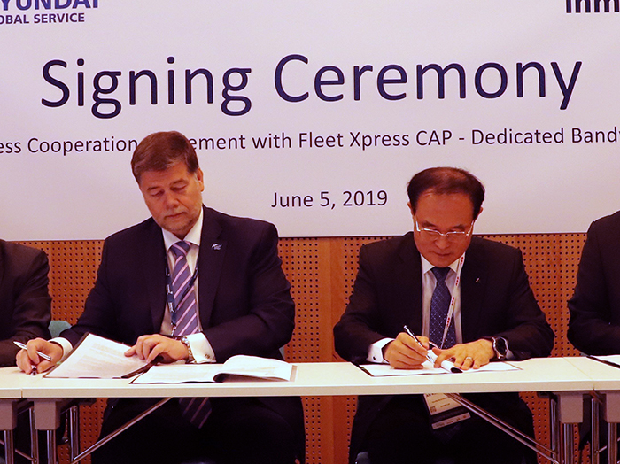 Two men in suits sign documents