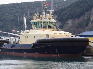 Tug boat with black hull and cream-color superstructure