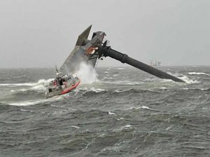 Capsized SEACOR Power on the evening of the accident, with a Coast Guard response boat in the foreground. [U.S. Coast Guard photograph]