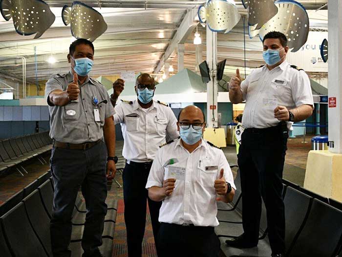 Crew members hold up vaccination cards