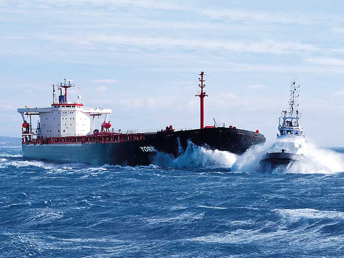 Tugboat at bow of large ship