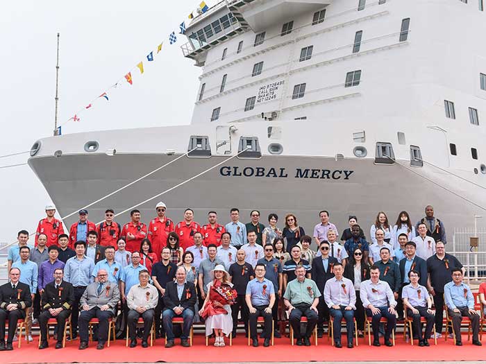 Group poses in front of hospital ship