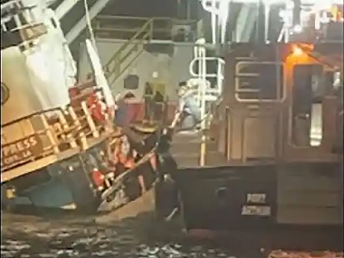 crewmembers are assisted off sinking tugs