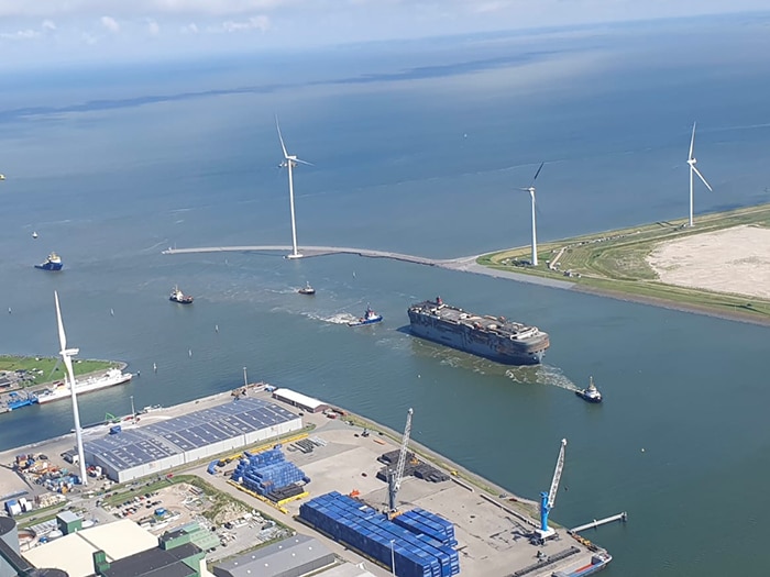 Burned out car carrier towed into port