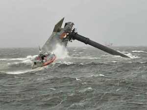 Capsized SEACOR Power on the evening of the accident, with a Coast Guard response boat in the foreground.