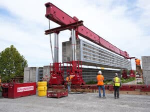 Barnhart crew members use a hydraulic power system to lift a prefabricated wall beam onto a barge for delivery to the Chickamauga Lock Replacement Project’s upstream approach wall contract near Watts Bar Dam Aug. 28, 2025. (USACE photo by Noe Gonzalez)