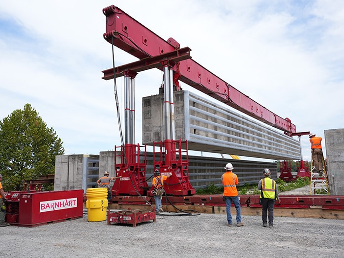 Barnhart crew members use a hydraulic power system to lift a prefabricated wall beam onto a barge for delivery to the Chickamauga Lock Replacement Project’s upstream approach wall contract near Watts Bar Dam Aug. 28, 2025. (USACE photo by Noe Gonzalez)