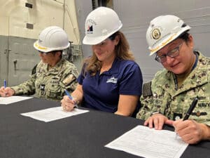 HII’s Ingalls Shipbuilding division delivered the Arleigh Burke-class guided missile destroyer Ted Stevens (DDG 128) to the U.S. Navy on December 29, 2025. Pictured from left to right are Prospective Commanding Officer for Ted Stevens (DDG 128) Capt. Mary Katey Hays, Ingalls Shipbuilding’s DDG Program Manager Lauren Daniel and SUPSHIP Gulf Coast’s DDG-51 Program Manager Representative Cmdr. Roxane Powers. [Photo: HII]
