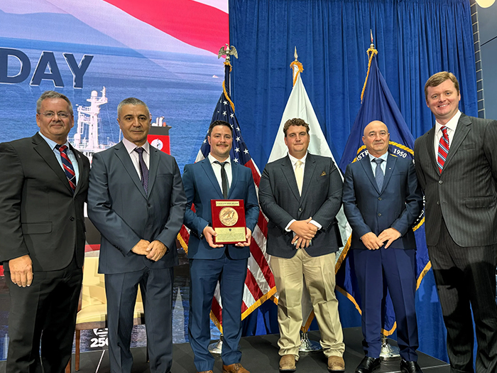Stena Immaculate crew members, along with union and Crowley leadership, standing side by side with Gallant Ship Award plaque L to R: Willie Barrere, President, American Maritime Officers; Dimeter Mitev, chief engineer, Crowley; Peter Skerys, second mate, Crowley; Thor Pearson, chief mate, Crowley; Ion Sterie, bosun, Crowley; James C. Fowler, executive vice president & division president, Shipping & Logistics, Crowley. [Photo: Crowley]