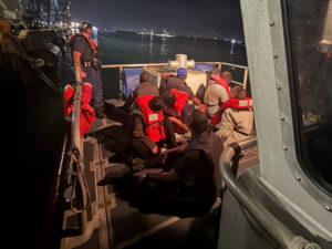 Coast Guard Station San Juan boat crew oversees a group of eight stowaway aliens apprehended moments earlier aboard the Charlotte Bridge barge as it was being towed into San Juan Harbor, May 22, 2026. [U.S. Coast Guard photo]