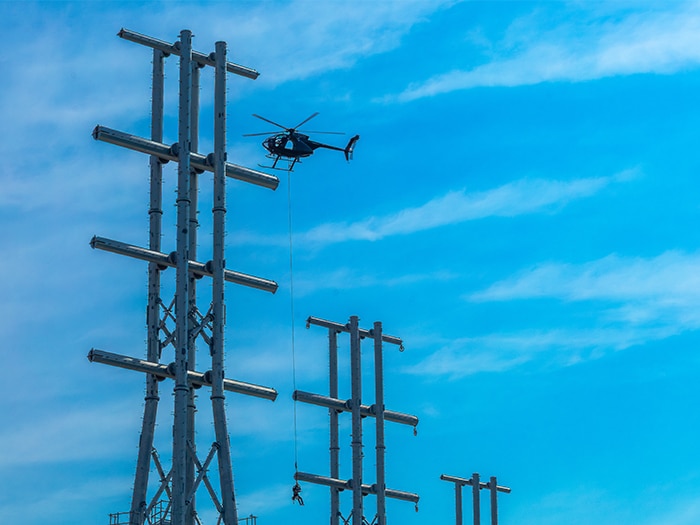 A lineman, lifted by helicopter, installs hardware to support raising the transmission lines to provide 205 feet of operational clearance for larger vessels calling JAXPORT’s Blount Island terminal. [Photo: JAXPORT]