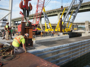 McKinney Salvage LLC, a subcontractor for CJ Mahan Construction Co., operates a heavy-lift derrick crane to guide a 420-ton concrete beam into position for the Chickamauga Lock Replacement Project's upstream approach wall.
